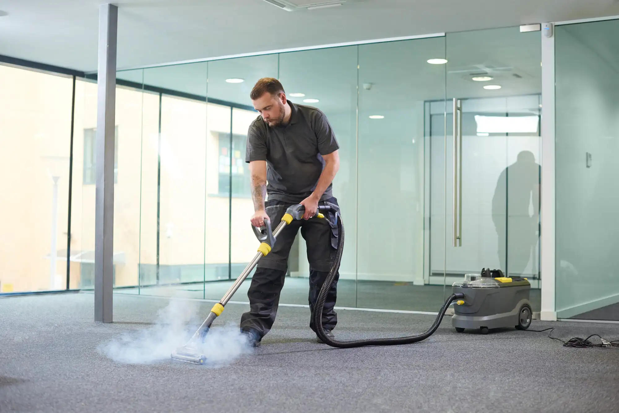 Man using industrial floor cleaning equipment in an office setting.