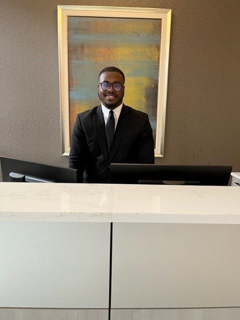 Man smiling while standing behind a desk.