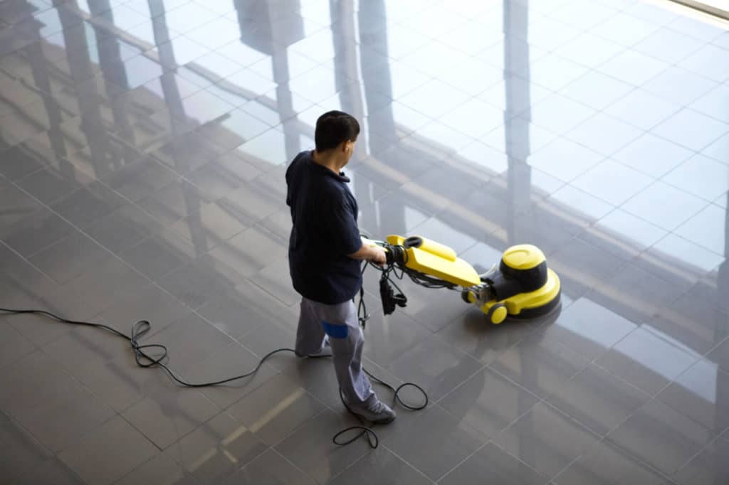 Overhead shot of a man operating a yellow floor buffing machine. The floor is very shiny.